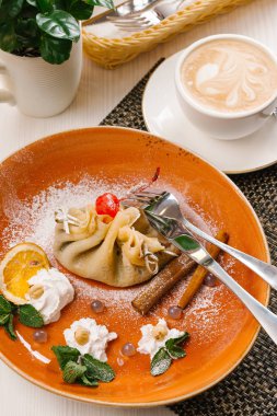 Doldurulmuş Krep ile portakal dilim servis ve kahverengi plaka üzerine krem şanti