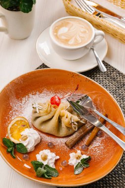 Doldurulmuş Krep ile portakal dilim servis ve kahverengi plaka üzerine krem şanti