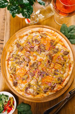 Peynirli pizza sığır eti, soğan ve ahşap tahta üzerinde sos ile