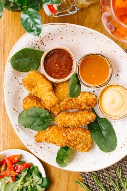 fesleğen yaprakları ve beyaz tabakta sosu üç tür ile servis tavuk Nuggets üstten görünüm