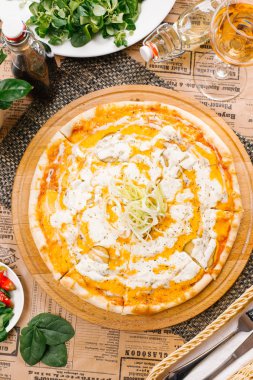 Ahşap tahta üzerinde pizza beyaz sos, soğan ve salatalık turşusu ile üstten görünüm