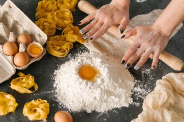 Kadın fettuccine makarna hamur siyah masaya haddeleme 
