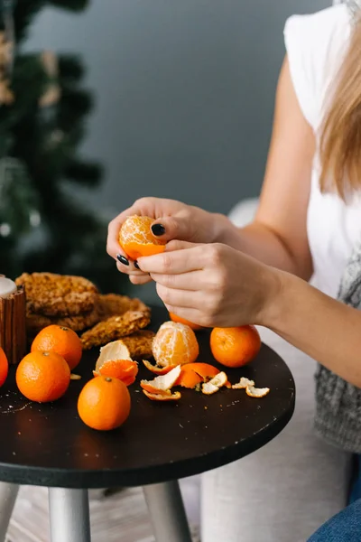 Young woman peeling tangerines on coffee table in living room