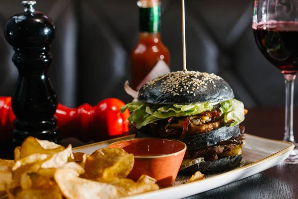 close up view of tasty burger with chips and sauce