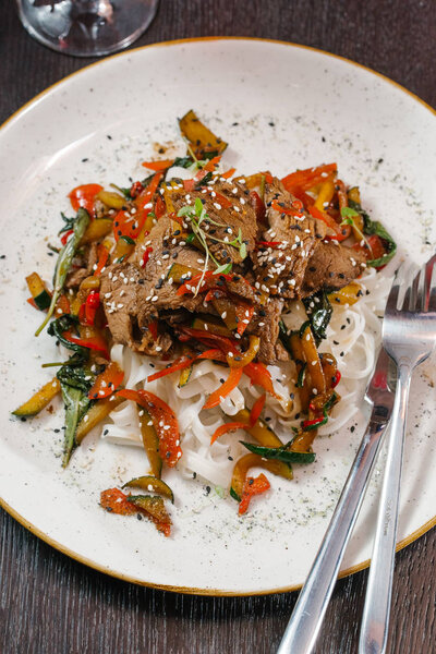 close up view of asian dish with meat, noodles and vegetables