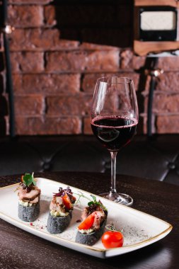 plaka üzerinde kırmızı şarap bruschettas et, sos ve kiraz domates ile cam görünümü kadar kapatın