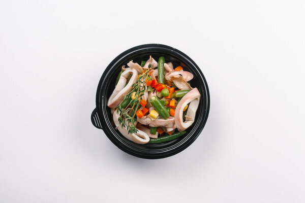Top view of proper nutrition of squid and vegetables salad in box on white background