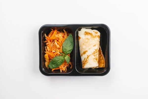 Top view of proper nutrition with vegetables salad and pancake in box on white background