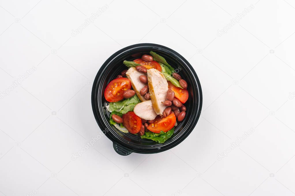 Top view of proper nutrition of chicken meat, vegetables and beans in box on white background