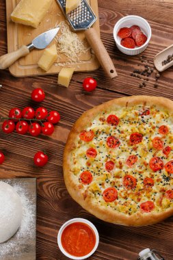 ahşap masa üzerinde beyaz sos, peynir ve dilimlenmiş domates ile pişmiş pizza üstten görünüm