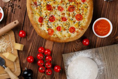 ahşap masa üzerinde beyaz sos, peynir ve dilimlenmiş domates ile pişmiş pizza üstten görünüm