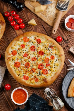 ahşap masa üzerinde beyaz sos, peynir ve dilimlenmiş domates ile pişmiş pizza üstten görünüm