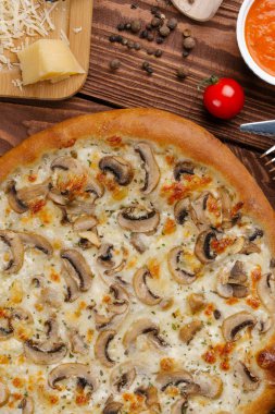 ahşap masa üzerinde beyaz sos, peynir ve dilimlenmiş mantar ile pişmiş pizza üstten görünüm