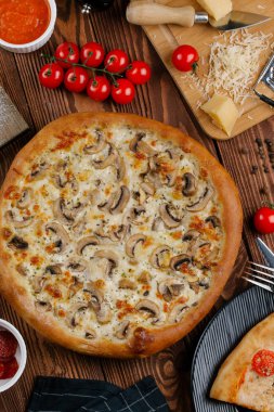 ahşap masa üzerinde beyaz sos, peynir ve dilimlenmiş mantar ile pişmiş pizza üstten görünüm