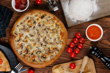 ahşap masa üzerinde beyaz sos, peynir ve dilimlenmiş mantar ile pişmiş pizza üstten görünüm