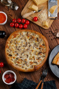 ahşap masa üzerinde beyaz sos, peynir ve dilimlenmiş mantar ile pişmiş pizza üstten görünüm