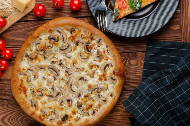 ahşap masa üzerinde beyaz sos, peynir ve dilimlenmiş mantar ile pişmiş pizza üstten görünüm