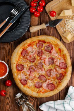 ahşap masa üzerinde pişmiş Pizza domates sosu, peynir, dilimlenmiş sosis ve pastırma ile üstten görünüm