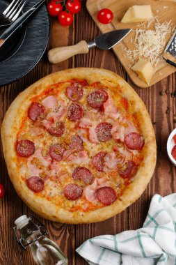 ahşap masa üzerinde pişmiş Pizza domates sosu, peynir, dilimlenmiş sosis ve pastırma ile üstten görünüm