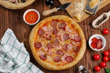ahşap masa üzerinde pişmiş Pizza domates sosu, peynir, dilimlenmiş sosis ve pastırma ile üstten görünüm