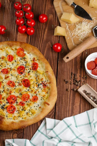 ahşap masa üzerinde beyaz sos, peynir ve dilimlenmiş domates ile pişmiş pizza üstten görünüm