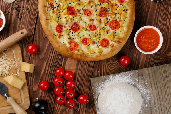 ahşap masa üzerinde beyaz sos, peynir ve dilimlenmiş domates ile pişmiş pizza üstten görünüm