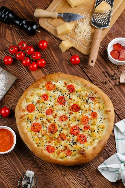 ahşap masa üzerinde beyaz sos, peynir ve dilimlenmiş domates ile pişmiş pizza üstten görünüm