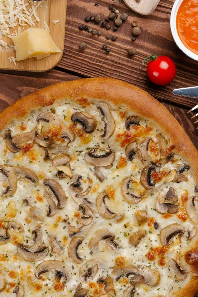 ahşap masa üzerinde beyaz sos, peynir ve dilimlenmiş mantar ile pişmiş pizza üstten görünüm