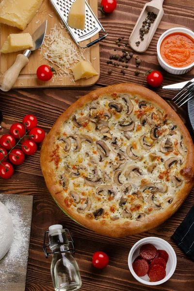 ahşap masa üzerinde beyaz sos, peynir ve dilimlenmiş mantar ile pişmiş pizza üstten görünüm