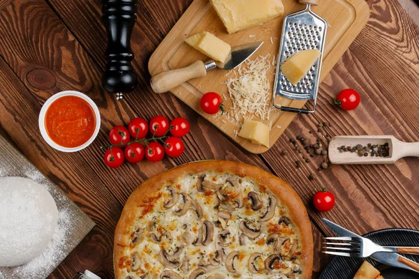 ahşap masa üzerinde beyaz sos, peynir ve dilimlenmiş mantar ile pişmiş pizza üstten görünüm