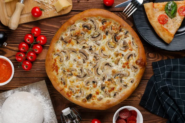 ahşap masa üzerinde beyaz sos, peynir ve dilimlenmiş mantar ile pişmiş pizza üstten görünüm