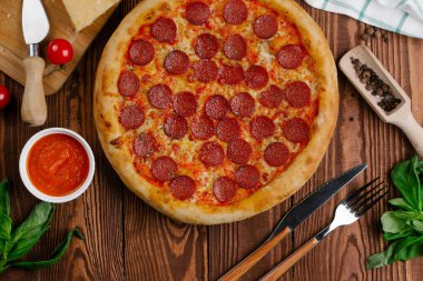 domates sosu, peynir ve dilimlenmiş sosis pişmiş pizza üstten görünüm ahşap tablo