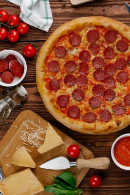 domates sosu, peynir ve dilimlenmiş sosis pişmiş pizza üstten görünüm ahşap tablo
