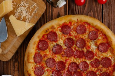 domates sosu, peynir ve dilimlenmiş sosis pişmiş pizza üstten görünüm ahşap tablo