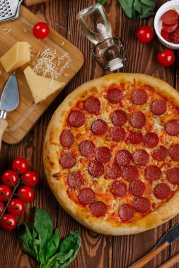 domates sosu, peynir ve dilimlenmiş sosis pişmiş pizza üstten görünüm ahşap tablo