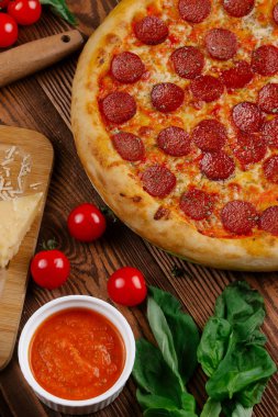domates sosu, peynir ve dilimlenmiş sosis pişmiş pizza üstten görünüm ahşap tablo