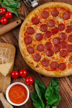 domates sosu, peynir ve dilimlenmiş sosis pişmiş pizza üstten görünüm ahşap tablo
