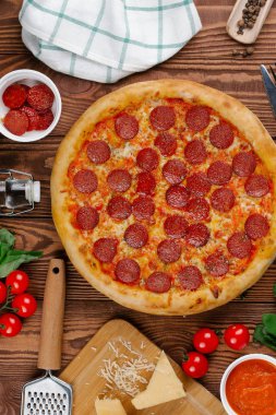 domates sosu, peynir ve dilimlenmiş sosis pişmiş pizza üstten görünüm ahşap tablo