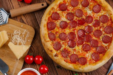 domates sosu, peynir ve dilimlenmiş sosis pişmiş pizza üstten görünüm ahşap tablo