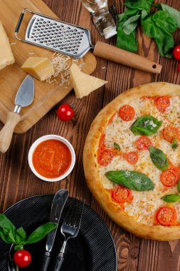 üstten görünüm Pizza domates, peynir ve taze fesleğen ile ahşap masaya servis bırakır
