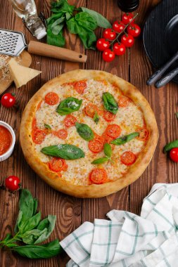 üstten görünüm Pizza domates, peynir ve taze fesleğen ile ahşap masaya servis bırakır