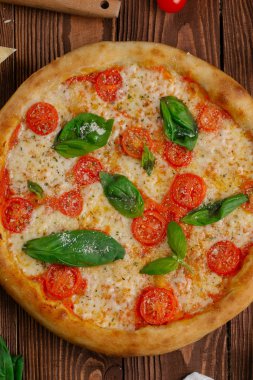 üstten görünüm Pizza domates, peynir ve taze fesleğen ile ahşap masaya servis bırakır