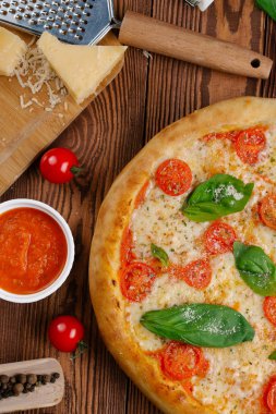 üstten görünüm Pizza domates, peynir ve taze fesleğen ile ahşap masaya servis bırakır