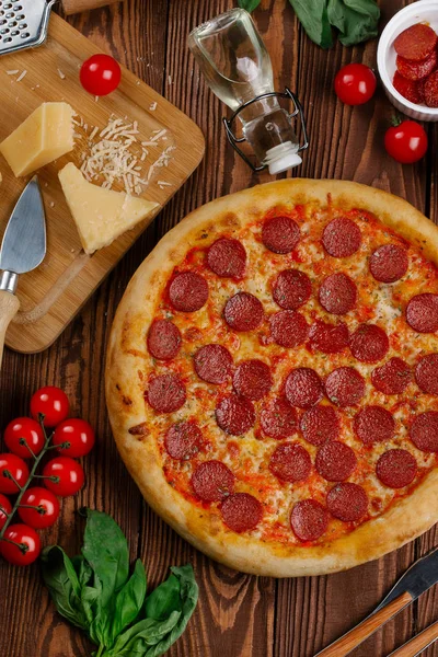 domates sosu, peynir ve dilimlenmiş sosis pişmiş pizza üstten görünüm ahşap tablo