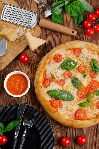 top view of pizza with tomatoes, cheese and fresh basil leaves served on wooden table