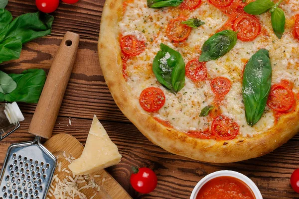 top view of pizza with tomatoes, cheese and fresh basil leaves served on wooden table
