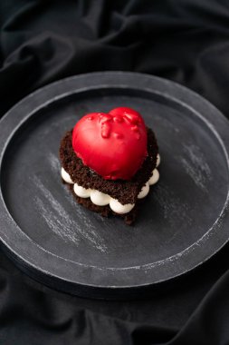 Koyu arka plan üzerinde kalp şeklinde lezzetli çikolatalı kek