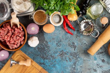 Çiğ kıyılmış et ve turkuaz arka plan üzerinde türler