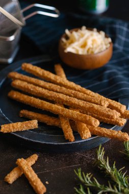 Kızarmış peynirli çubuk karanlık plaka üzerinde