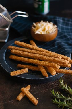 Kızarmış peynirli çubuk karanlık plaka üzerinde